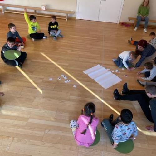 Kinder sitzen im Turnsaal am Boden und spielen