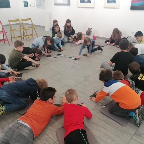 Kinder sitzen im Kreis und malen.