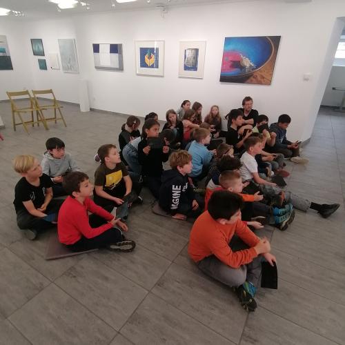 Kinder sitzen am Boden und hören zu