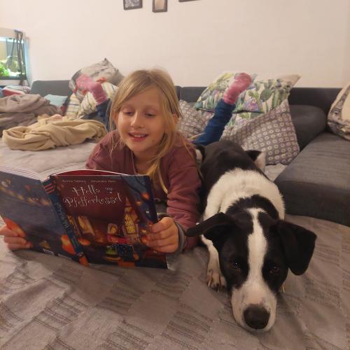 Mädchen liest ihrem Hund ein Buch vor