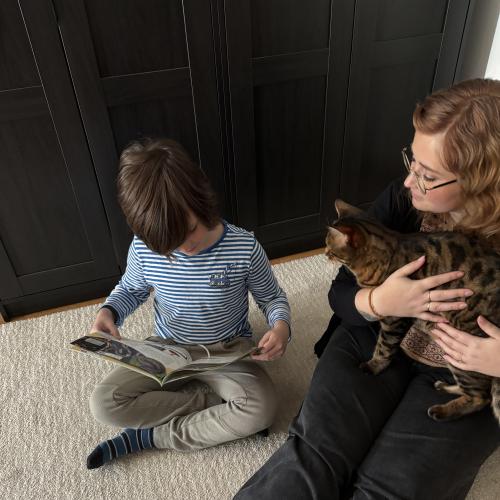 Bub liest einem Mädchen und ihrer Katze vor
