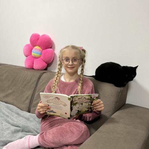 Mädchen liest ihrer Katze ein Buch vor