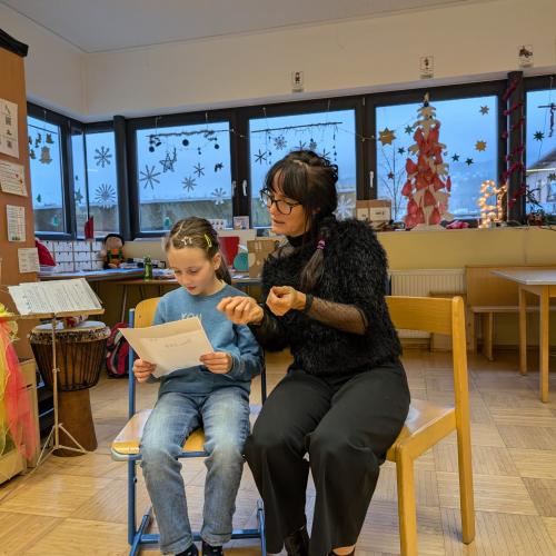 Mädchen liest, Lehrerin zeigt Gebärden mit