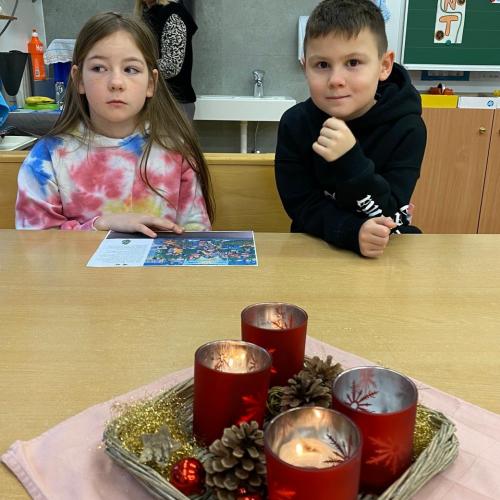 Mädchen und Bub sitzen am Adventkranz