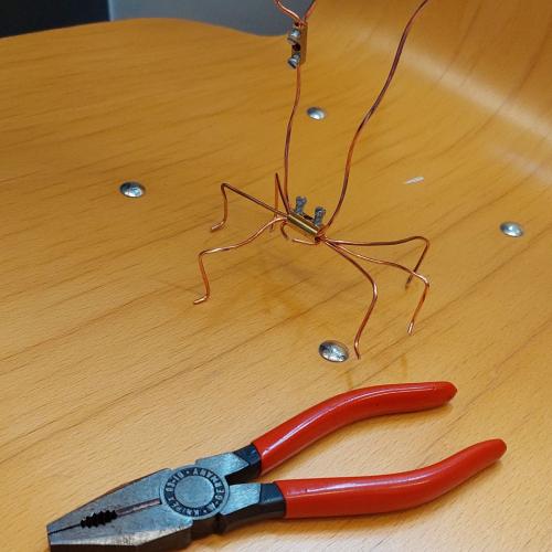 Krebs aus Draht, daneben liegt eine Kombizange
