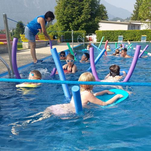 Kinder schwimmen mit der Schwimmnudel im Wasser