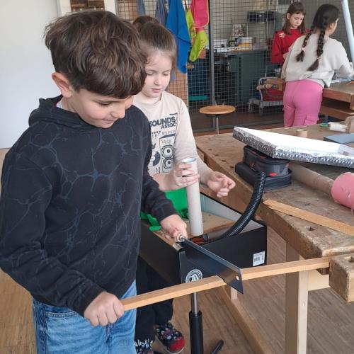 Buben sägen ein Brett ab