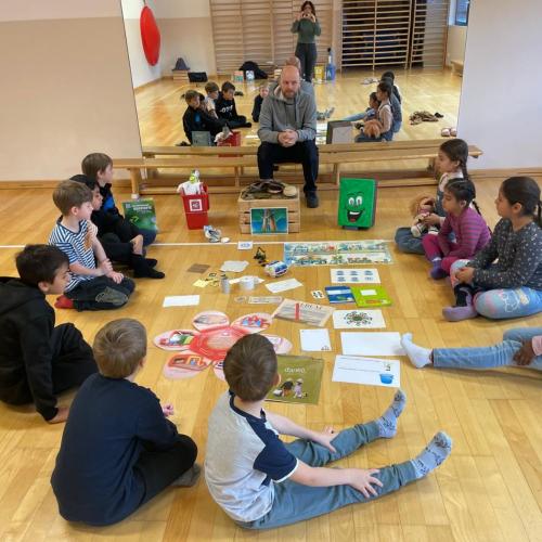 Kinder sitzen im Kreis um Robi und hören ihm zu
