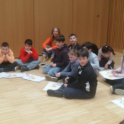 Kinder arbeiten gemeinsam am Boden eines großen Raumes