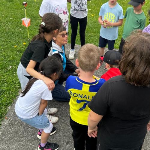 Kinder stehen im Kreis um die Trainerin herum