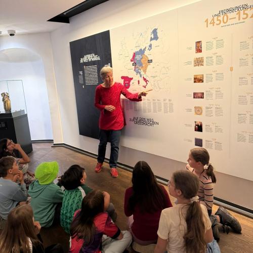 Kinder lauschen einer Erklärung im Museum