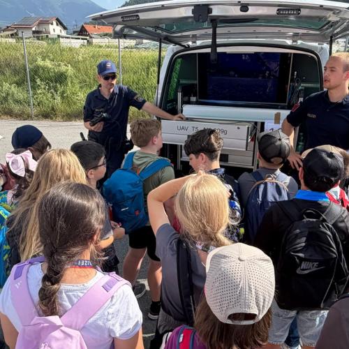 Polizisten erklären einer Kindergruppe, was sie im Auto alles mitführen