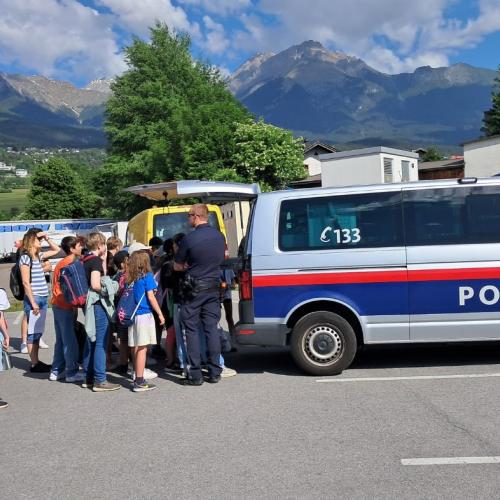 Kindergruppe steht bei einem Polizeiauto