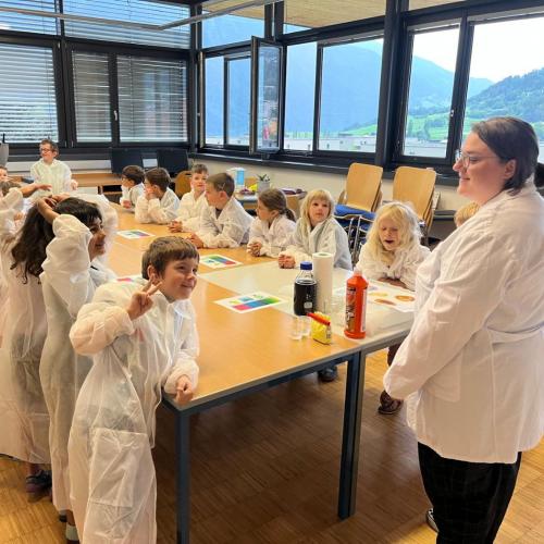 Kinder mit weißen Mänteln stehen um den Tisch