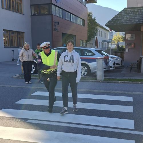 Mädchen geht mit Polizistin über den Zebrastreifen