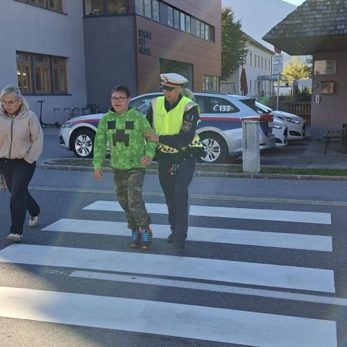 Bub überquert gemeinsam mit der Polizistin die Straße