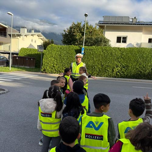Kinder gehen mit der Polizistin zum Zebrastreifen