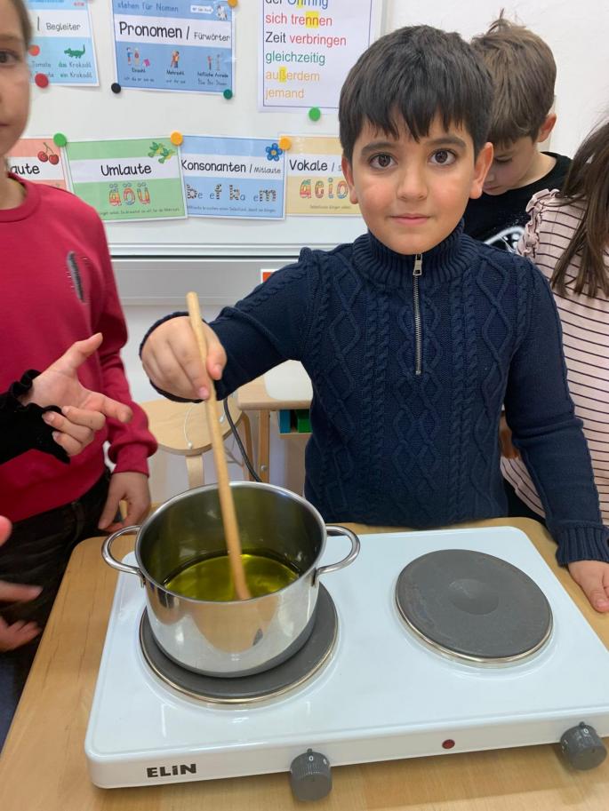 Bub steht am Herd und rührt die Flüssigkeit im Topf