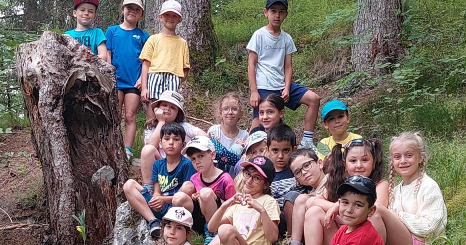 Kinder sitzen neben einem ausgehöhlten Baumstumpf im Wald