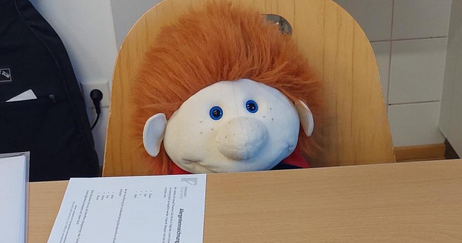 Handpuppe sitzt am Schreibtisch