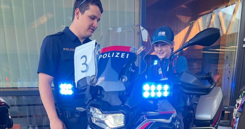 Bub sitzt auf dem Polizeimotorrad und darf das Blaulicht einschalten