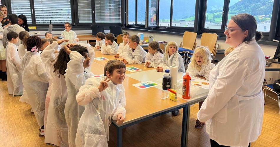 Kinder mit weißen Mänteln stehen um den Tisch