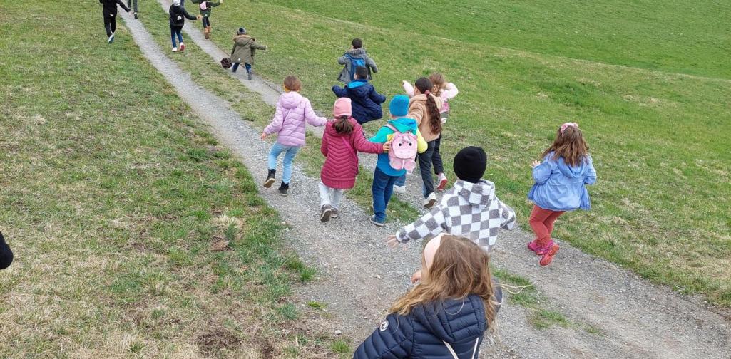 Kinder laufen auf einem Feldweg den Hügel hinunter
